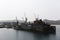 A quiet passage stands on the water in Slavyanka Bay with a ship being repaired in it.