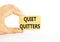 Quiet quitters symbol. Concept words Quiet quitters on wooden blocks. Beautiful white table white background. Businessman hand.