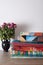 Quilts stacked and bouquet of dried roses in vase on white wall background