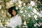 Quince white flowers on tree branch on background of blurred boho girl enjoying aroma from tree in spring garden. Cydonia oblonga