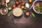 Quinoa in bowl with wooden spoon and vegetables and seasoning cooking ingredients on rustic background