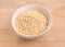 Quinoa flakes in a round glass bowl on wood