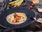 Quinoa porridge with fruits, strawberries, pear, banana and coconut milk in plate over grey background. Healthy breakfast