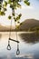 Quintessential beautiful English Summer landscape image of child`s rope swing over calm lake in Lake District during golden Summe