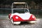 Quirky water boat with white and red paint. It is parked in the sandy, rocky seashore. It is settled in an island and used for the