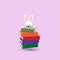 Rabbit hiding behind on a stack of colorful books
