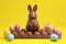 rabbit shaped chocolate with easter eggs isolated yellow