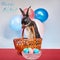 Rabbit stands in a basket near Easter eggs in a vase