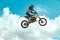 Racer on motorcycle dirtbike motocross cross-country in flight, jumps and takes off on springboard against sky. Concept