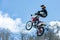 Racer on a motorcycle in flight, jumps and takes off on a springboard against the snowy mountains
