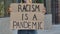 RACISM IS A PANDEMIC on cardboard poster in hands of female protester activist. Stop Racism concept, No Racism. Rallies