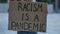 RACISM IS A PANDEMIC on cardboard poster in hands of female protester activist. Stop Racism concept, No Racism. Rallies