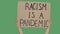 RACISM IS A PANDEMIC. Protest text message on cardboard. Stop racism. Police violence. Banner design concept. Hands