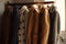 a rack of coats hanging on a rail next to a window with a window sill in the background and a coat rack in the foreground