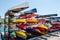 Rack of colorful kayaks and canoes.