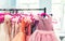 Rack with many beautiful holiday dresses for girls on hangers at children fashion showroom indoor. Kid girl dress hire studio for