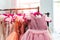 Rack with many beautiful holiday dresses for girls on hangers at children fashion showroom indoor. Kid girl dress hire studio for