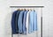 Rack with stylish men`s clothes near brick wall