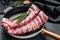 Rack of uncooked raw pork spare ribs seasoned with spices in a pan. Black background. Top view