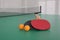 Rackets and balls on ping pong table indoors