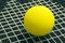 Racquetball on racket strings. Yellow frontenis ball laying on r