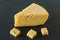 Radamer cheese on a black concrete background. triangular piece of yellow cow`s milk swiss cheese with holes