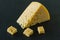 Radamer cheese on a black concrete background. triangular piece of yellow cow`s milk swiss cheese with holes