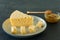 Radamer cheese on a plate served with honey. triangular piece of yellow cow`s milk swiss cheese with holes