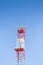 Radar antenna on a metal structure colored in red and white against a blue background - image with copy space