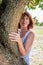 Radiant 50s woman smiling next to a tree for mature wellness