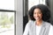 A radiant African-American businesswoman smiles warmly in an office setting