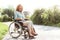 Radiant disabled lady laughing while sitting in wheelchair outdoors