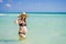 Radiant and expecting, a pregnant woman stands on a pristine snow-white tropical beach, celebrating the miracle of life