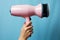 Radiant grooming Womans hands, hair dryer on blue pink background, embracing beauty