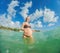 A radiant pregnant woman revels in the serenity of the turquoise sea, embracing the soothing waves as she celebrates the