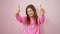 Radiant young hispanic woman flashing you a thumbs up gesture, confidently standing over an isolated pink background. a picture-