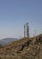 Radio antennas in the middle of the mountain, dry landscape with tall antennas, sunny sky, communication antennas, and hut in