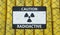Radioactive caution sign on chain link fence and many barrels with nuclear waste in background. 3D rendered illustration