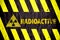 Radioactive ionizing radiation danger symbol and word with yellow and black stripes painted on a massive concrete wall