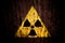 Radioactive ionizing radiation nuclear danger yellow symbol cracked concrete wall.