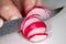 A radish being clipped thinly bu the chef on a cutting board