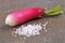 Radish next to fleur de sel close-up on gray background