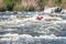 Rafting, kayaking. Close-up view of oars with splashing water. A man in a small kayak in a stormy stream of water.