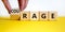 Rage or courage symbol. Businessman turns a cube and changes the word `rage` to `courage`. Beautiful yellow table, white