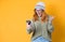 Rage girl using the mobile phone, isolated on yellow background. Furious young woman looks to smartphone