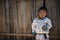 Ragged body boy Wearing poor looking old clothes, standing at a woven bamboo wall in a rural village in northern Thailand