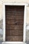 Ragged brown wooden door in a stone wall close-up of village house. Italy .