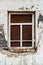 The ragged wall of an old abandoned building, with a window closed by a sheet of rusty metal