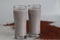 Ragi Malt, wholesome ragi delight. Two tall glasses of nutritious ragi porridge and a scattered spread of ragi grains around