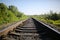 Rail tracks in the green field. Railway transport industry. Empty road on summer day. Travel lifestyle motivation photo